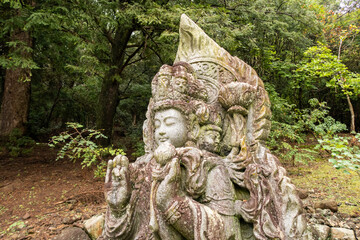 Fototapeta na wymiar Wayside carved stone small Buddha statue in japanese Nara park in Nara, Japan.