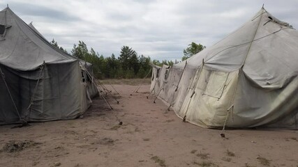old soldiers canvas tents torn in the wind in the field. Tent city on military exercises