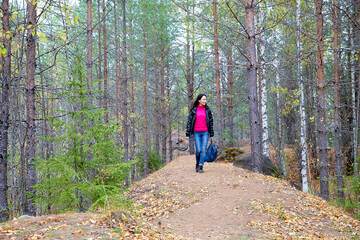 Fototapeta premium Beautiful young woman walking in the forest with sprice in autumn