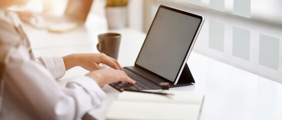 Businesswoman working on digital tablet, mug and stationery on counter bar