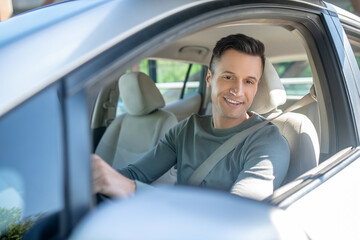 Young adult smiling man driving a car