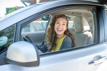 Smiling young adult woman sitting in a car.