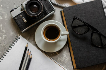 old camera on the table with a cup of coffee, a book and glasses
