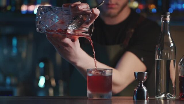 bartender mixing classic negroni cocktail with rum and ice