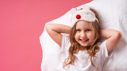 little girl in a sleep mask is lying on a pillow with her hands behind her head