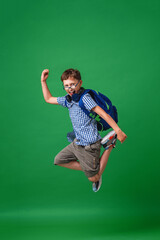 cheerful mischievous schoolboy with glasses and a backpack jumps