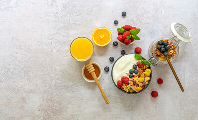 Obraz na płótnie Canvas Healthy breakfast concept. Bowl of homemade granola muesli with yogurt, fresh raspberries, blueberries and honey. Top view, copy space