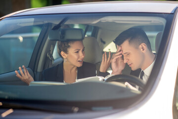 Business woman and man talking seriously in a car