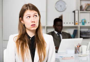 Upset  woman  and man colleague working with laptop on background in office
