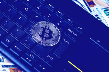 Dollar bills, black keyword and metal souvenir bitcoin. The concept of electronic money, online...