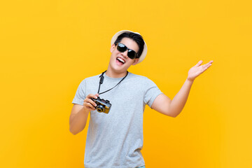 Happy smiling handsome young Asian male tourist with hand open gesture and camera isolated on...