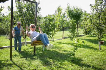 Vertical image of a mature couple in-love on a tree swing outside