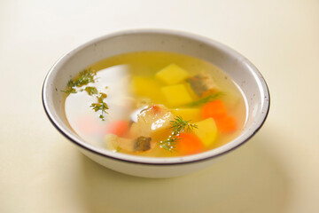 Delicious stew soup with meat and vegetables served in a white bowl over bright pastel yellow background. Healthy diet.