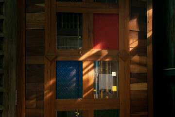 Light beam casting on wooden door with colored glass