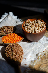 raw buckwheat, lentils and chickpeas in wooden spoons on the table