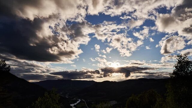 Time lapse of a sunset in the mountains of Norway. Clouds are changing shape in and the sun is hiding behind a cloud and then bursts out before creating spectacular light. Shot in Hallingdal in 4K.