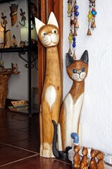 Tall wooden carved cats displayed in a shop doorway, Mijas, Spain.