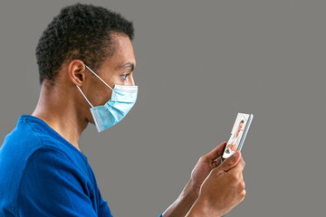 view of a afro-american young man with aCovid 19 proctection mask having an online consultation with his doctor