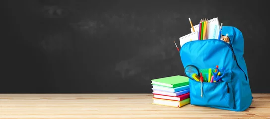 School bag. Backpack with supplies for school on the background of black blackboard. Copy space for text © adragan