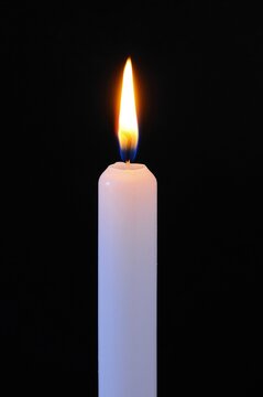 White Candle Against A Black Background.