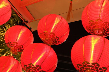 Fototapeta na wymiar filled frame background wallpaper photo of Chinese red paper lanterns with beautiful patterns and soft red light hanging from a ceiling during the celebration of lunar new year