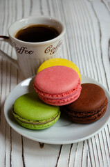 different macaroons on a white background with a cup of coffee