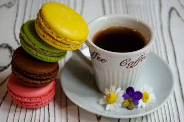 different macaroons on a white background with a cup of coffee