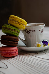 different macaroons on a white background with a cup of coffee