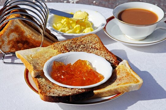 Buttered toast with marmalade with cup of tea to the rear,