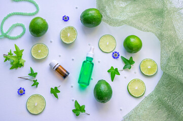 Face anti-aging serum and essence oil in bottles, lime slices, green leaves on white background - using citrus and vitamin C for cosmetic products concept