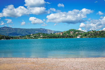 
Beautiful summer landscape - sea bay with calm turquoise water, white clouds on blue sky, green trees and mountains on the horizon.
