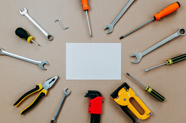 Tools top view on craft paper. Plier, open wrenches, screwdrivers and staple gun lay in circle with...
