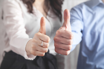 Businessman and businesswoman showing thumb up gesture. Success