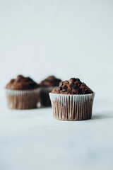 Beautiful chocolate muffins with pieces of chocolate on a white background with place for text