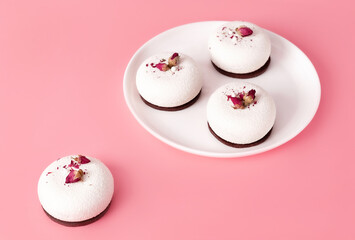 Mousse pastry dessert covered with white chocolate and decorated with rose buds on pastel pink background. Modern stylish cake. Copy space. Close-up.