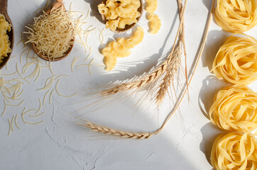 different types of raw pasta on a white background in
 wooden spoons