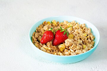 Homemade crunchy granola with nuts, dried fruits, fresh strawberries,  on a white plate. Healthy breakfast concept.