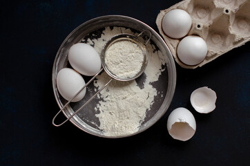 ingredients for cookies. cookie cutters on a dark background with flour and a rolling pin