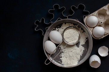 ingredients for cookies. cookie cutters on a dark background with flour and a rolling pin