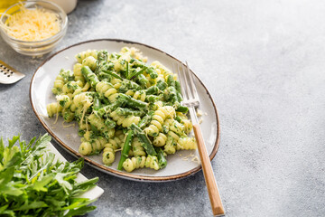 pasta with green vegetables and creamy sauce. fusilli pasta with asparagus beans and spinach on grey stone background