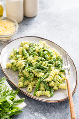 pasta with green vegetables and creamy sauce. fusilli pasta with asparagus beans and spinach on grey stone background
