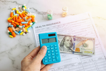 One hundred us dollar on insurance paper bill, calculator and medicine pills. Health care cost concept