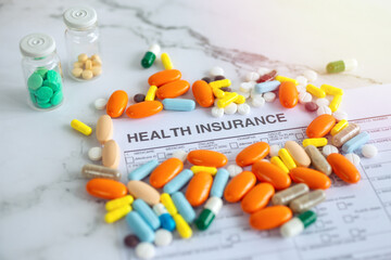 Close up of colorful medicine pills on insurance paper bill. Health care concept