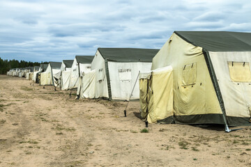 old soldiers ' canvas tents torn in the wind in the field. Tent city on military exercises