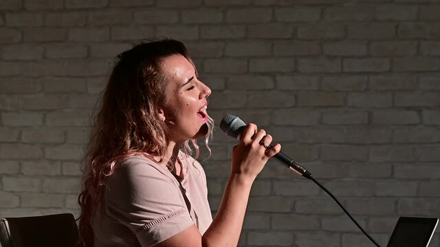 Woman recording vocal lesson using laptop while staying at home. The teacher sings a song into the microphone. A professional singer has a video blog.