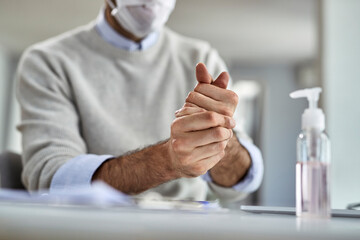 Close-up of a businessman using hand sanitizer while working at home.