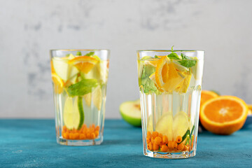 orange water with sea buckthorn and mint in glasses on blue background