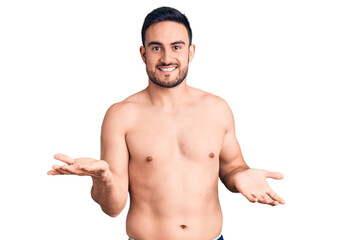 Fototapeta premium Young handsome man wearing swimwear smiling cheerful with open arms as friendly welcome, positive and confident greetings