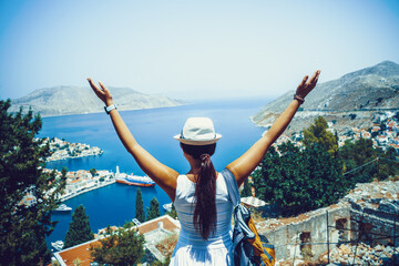 Back side of young traveling woman walking and looking in Greek island of Symi, Dodecanese, Greece.