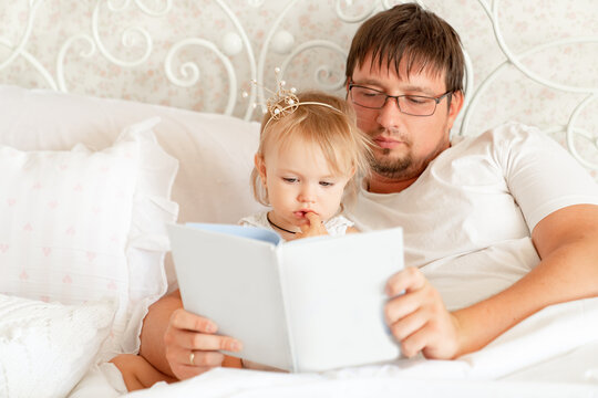 parents reading book to daughter in bed. place for text on white paper.